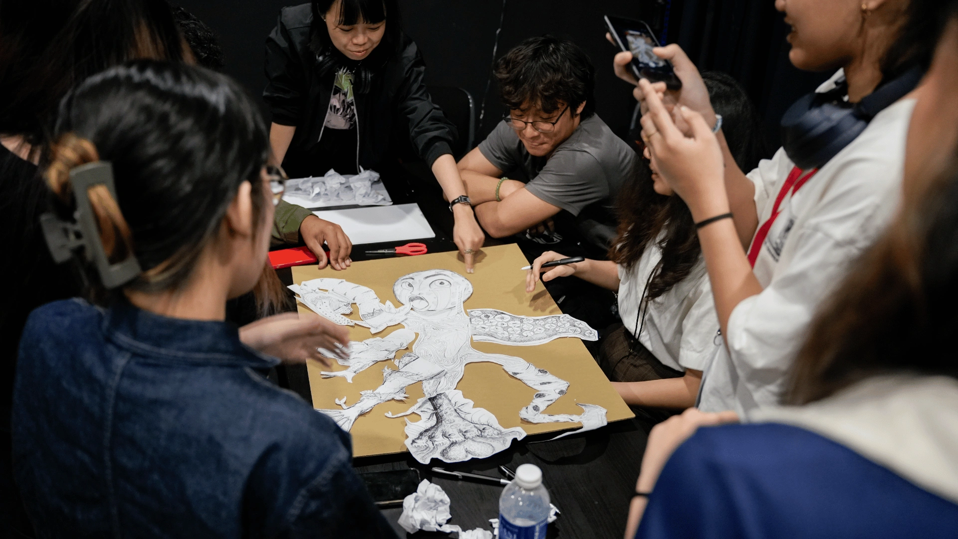 Students assembling their cut-out, Frankenstein-like monster from separately drawn parts during the Build Battle: Monster Mashup activity at Summit Day 2026